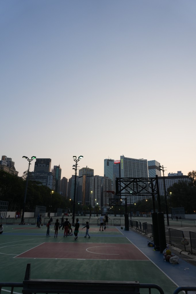 Evening basketball game with the city skyline behind the court